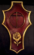 A cross within a circle symbolizing the Earth and a rose beneath