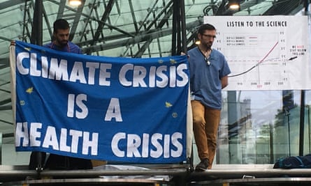 Two doctors hold a banner reading ‘Climate crisis is a health crisis’.