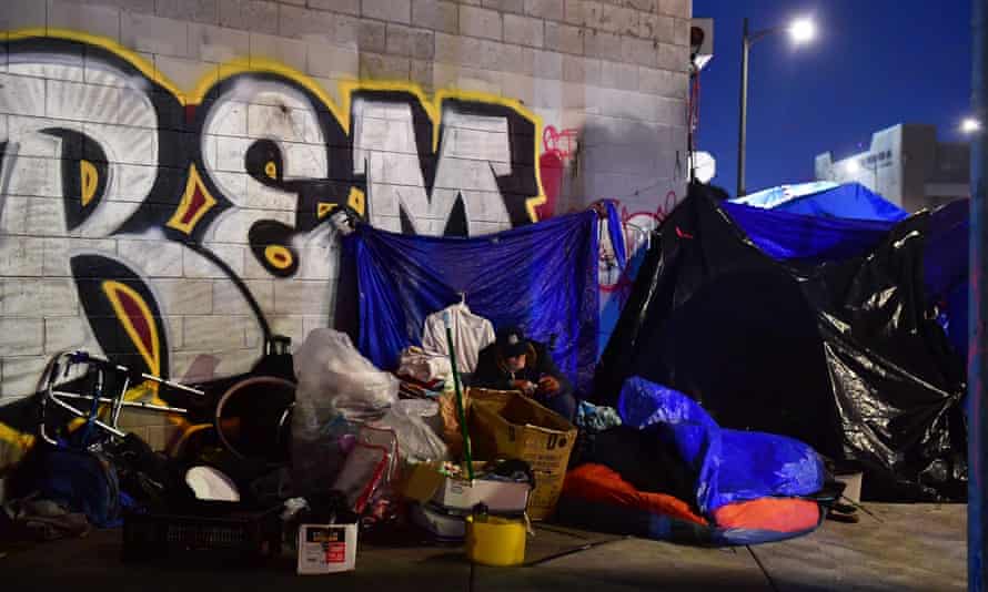 blue tents propped against a wall with some painted graffiti on it