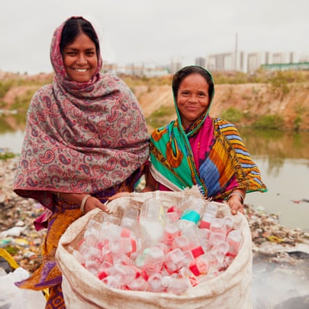 Two women smiling and holding a bag full of plastic bottles