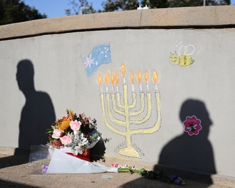 People walk past a memorial drawn on the wall of the pedestrian bridge at Bondi beach.
