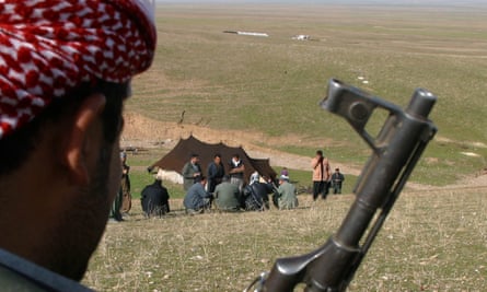 A Kurdish fighter guards Iraqi refugees at a camp in Erbil