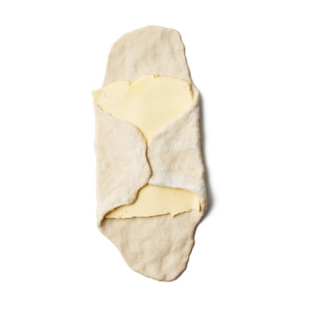 Roll out the dough on a lightly floured surface to about the same size as the butter rectangle, then, keeping this central rectangle thicker, roll or stretch out the sides so you end up with a cross shape, with four thin arms and a thick, butter-sized rectangle in the centre.