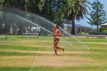 A woman runs under a water sprinkler in the suburb of Semaphore in Adelaide on a hot day. Temperatures were forecast to rise to 41C on Wednesday across South Australia.