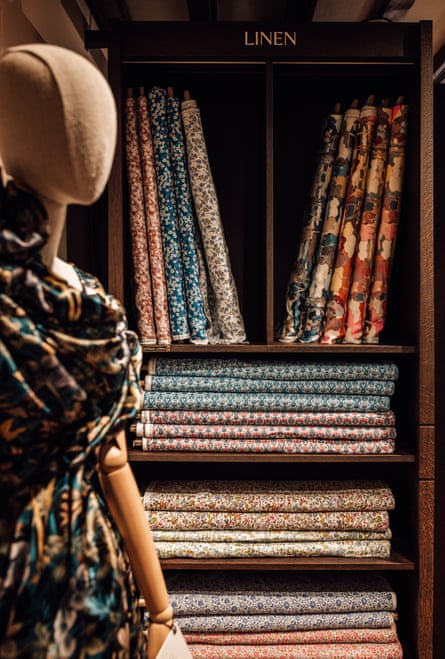 A mannequin next to shelves containing fabric in the Liberty store in London