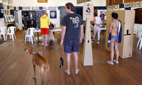 People in beach attire inside a surf lifesaving club being used as a voting centre