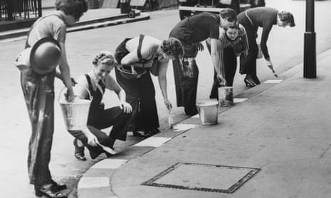 Women in a civil defence unit paint white squares along the kerb to facilitate night-time driving in London, September 1939.