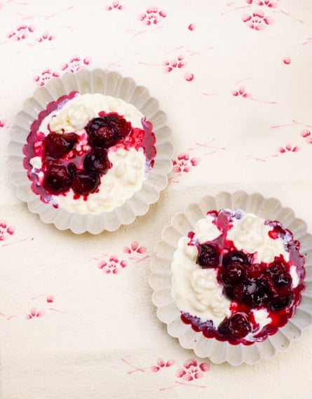 Two white bowls of rice pudding with plum sauce.