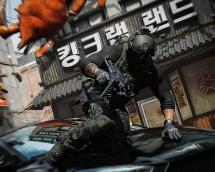 A soldier is seen clambering on the hood of a car.