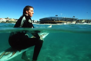 Surfer James Mohr in front of the Beach Volleyball stadium on Bondi Beach that was built for the Olympics.