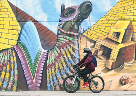 A person wearing a mask cycles past a climate change-themed nature mural on Earth Day during the Covid-19 pandemic in Toronto, Canada.