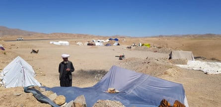 A man stands in the desert with tents