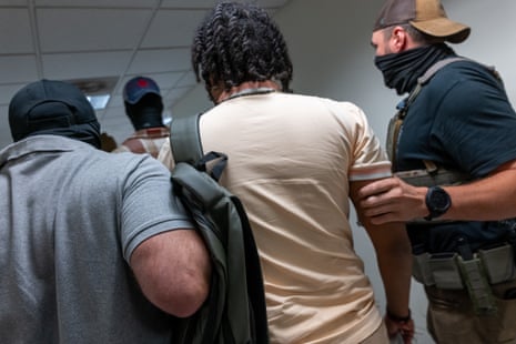 Federal agents escort a detained man through a corridor at immigration court