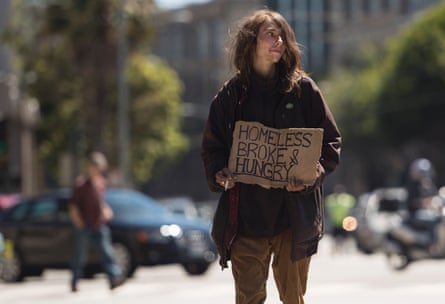 A homeless man begs on a center divider in San Francisco, California