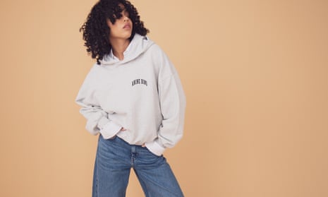 A model with curly hair wears an ecru hoodie with wide leg jeans.
