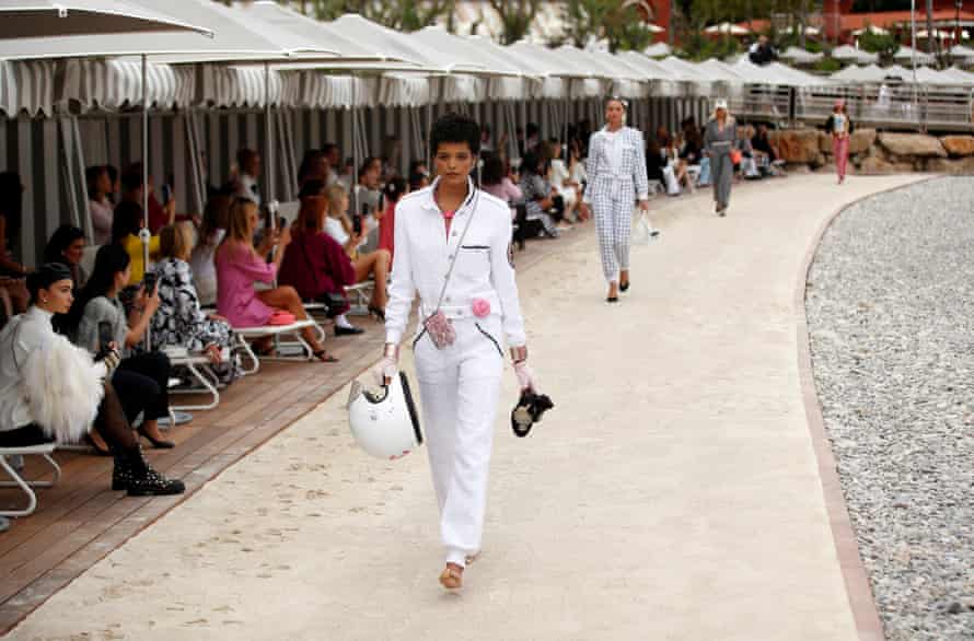 Models in jumpsuits walk past people on sun loungers