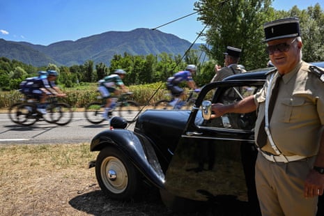 Spectators dressed in vintage French gendarmerie uniforms cheer along the roadside at the Tour de France.