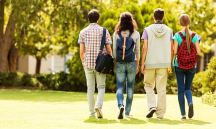 A view of a group of young students walking in a park from behind