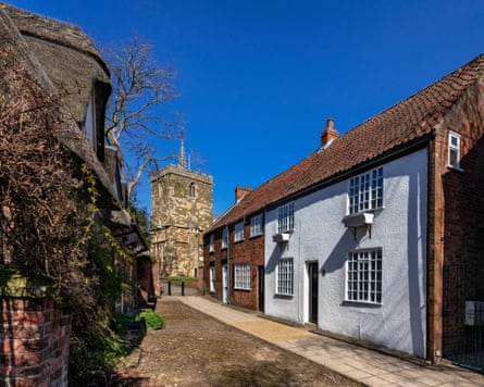 Cottages on a town street with a church tower in the background.