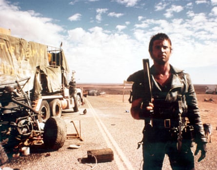 rugged-looking man holds a gun in the post-apocalyptic desert