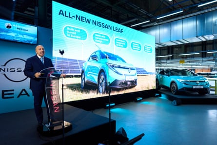 Massimiliano Messina speaks at a podium next to a large screen with the words ‘All-new Nissan Leaf’ over a photograph of a car