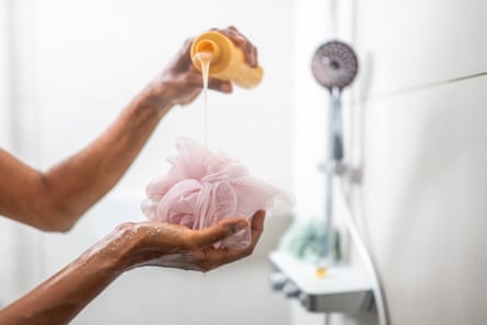 Woman pouring shower gel on bath sponge while taking a shower