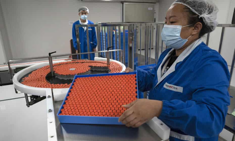 a worker feeds vials for production of SARS CoV-2 Vaccine for COVID-19 at the SinoVac vaccine factory in Beijing