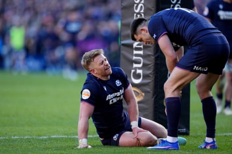 Scotland's Kyle Steyn holds his leg after receiving a gash to his leg while failing to stop France's Antoine Dupont scoring a try.