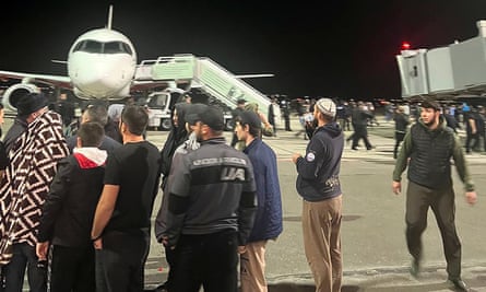People in a crowd on the airfield shout antisemitic slogans