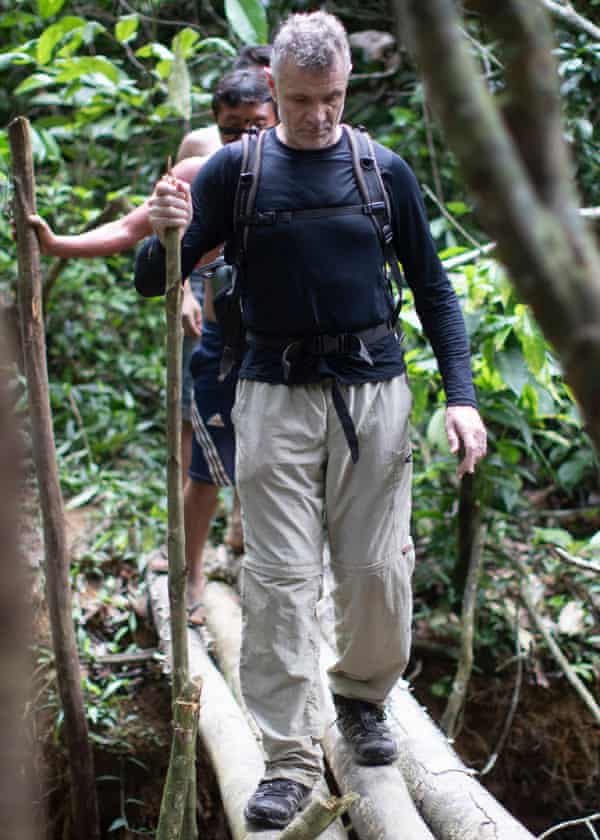 Dom Phillips crossing bridge with Indigenous people behind him