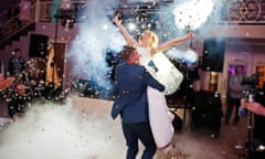 Newly married couple dancing on their wedding party with heavy smoke and multicolored lights on the background