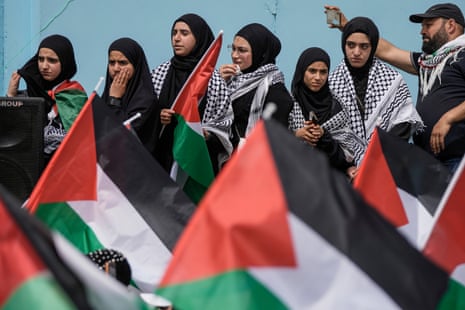 A group of women and one man are pictured besides Palestinian flags as hundreds of Palestinian refugees protested on Thursday outside the offices of Unrwa in Beirut, expressing solidarity with fellow Palestinians in the Gaza Strip.