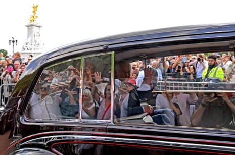 King Charles III waves as he arrives by car at Buckingham Palace