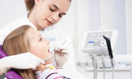 A dentist checks a girl’s teeth