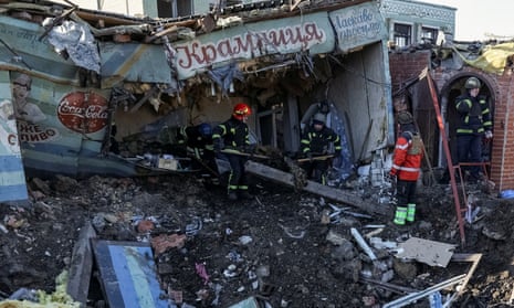 Ukrainian firefighters work at the site of a local market in Shevchenkove.