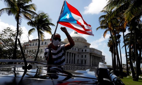 A man holds a Puerto Rican national flag during a protest against the school reopening this week. Over the past half century Puerto Rico has held six non-binding referendums on its status.
