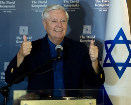 Lindsey Graham smiles and gives the thumbs up beside an Israeli flag