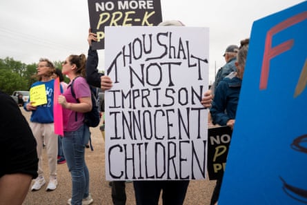 People hold signs, one of which says “Thou Shalt Not Imprison Innocent Children.”