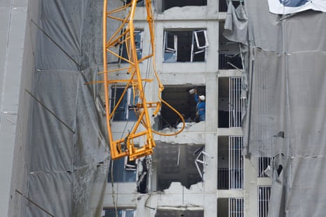 A view of a damaged crane, as construction workers inspect damage in a building that was under construction, in Bangkok, Thailand.
