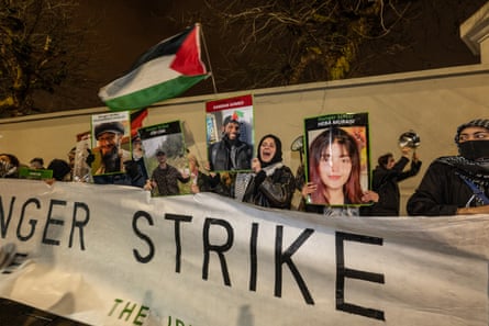 Demonstrators hold flags and pictures of the Palestine Action prisoners on hunger strike