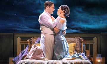 a man and a woman kneeling on a bed on a stage