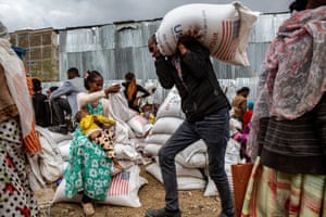 A man carries a sack of grain as people gather at a food distribution centre in Mekelle