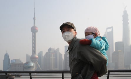A man and his child wear masks to protect them from heavy smog as they visit Waitan in December 2013 in Shanghai, China.