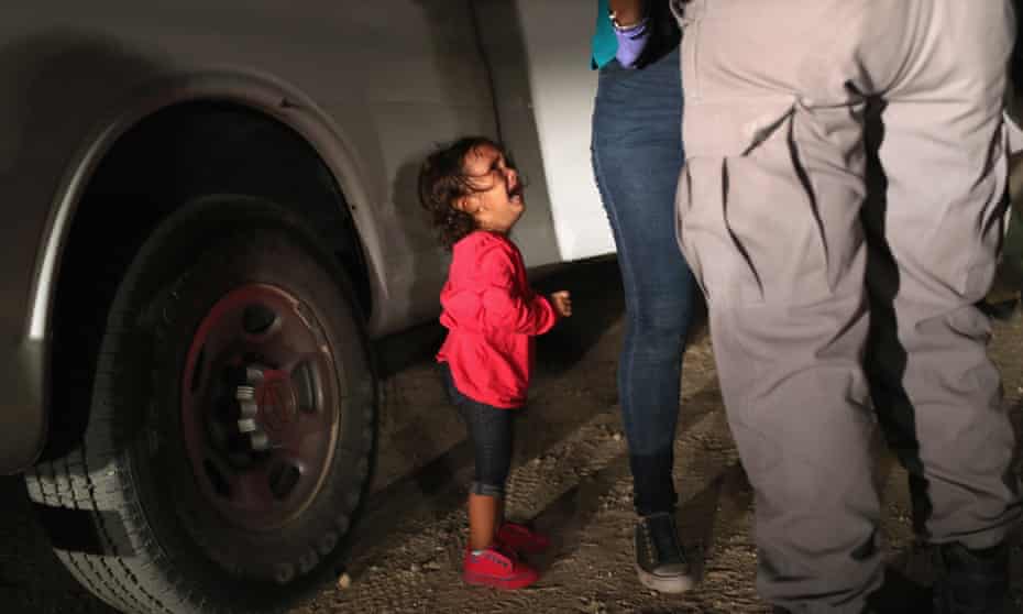 A two-year-old Honduran asylum seeker cries as her mother is searched and detained near the US-Mexico border, in McAllen, Texas
