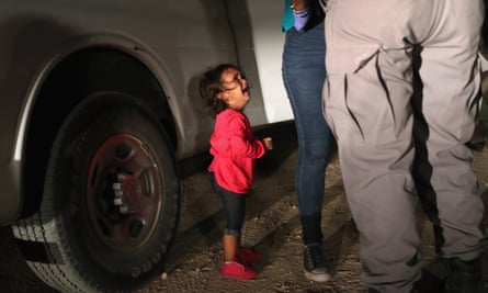 A two-year-old Honduran girl cries as her mother is searched and detained near the US-Mexico border