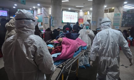 Medical staff wearing arrive with a patient at the Wuhan Red Cross hospital on Saturday. The virus has now killed 56 people.