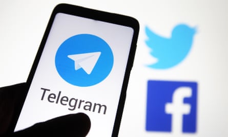 Telegram logo seen on a mobile phone screen in front of Facebook and Twitter logos
