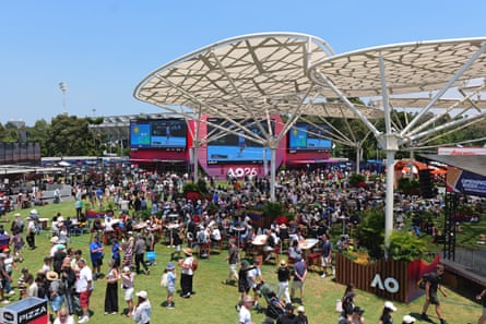 Crowds at Melbourne park standing on grass with large screens showing tennis