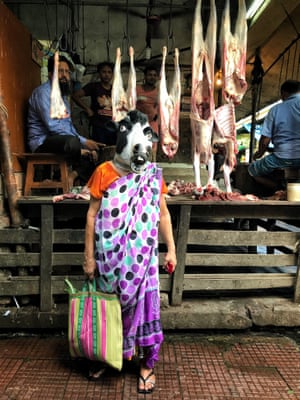A woman in a cow mask at a butcher's shop