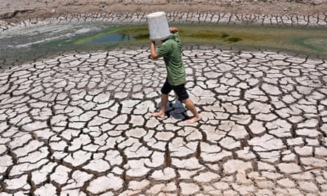 A man shields from the sun as he crosses a dried-up pond in Vietnam